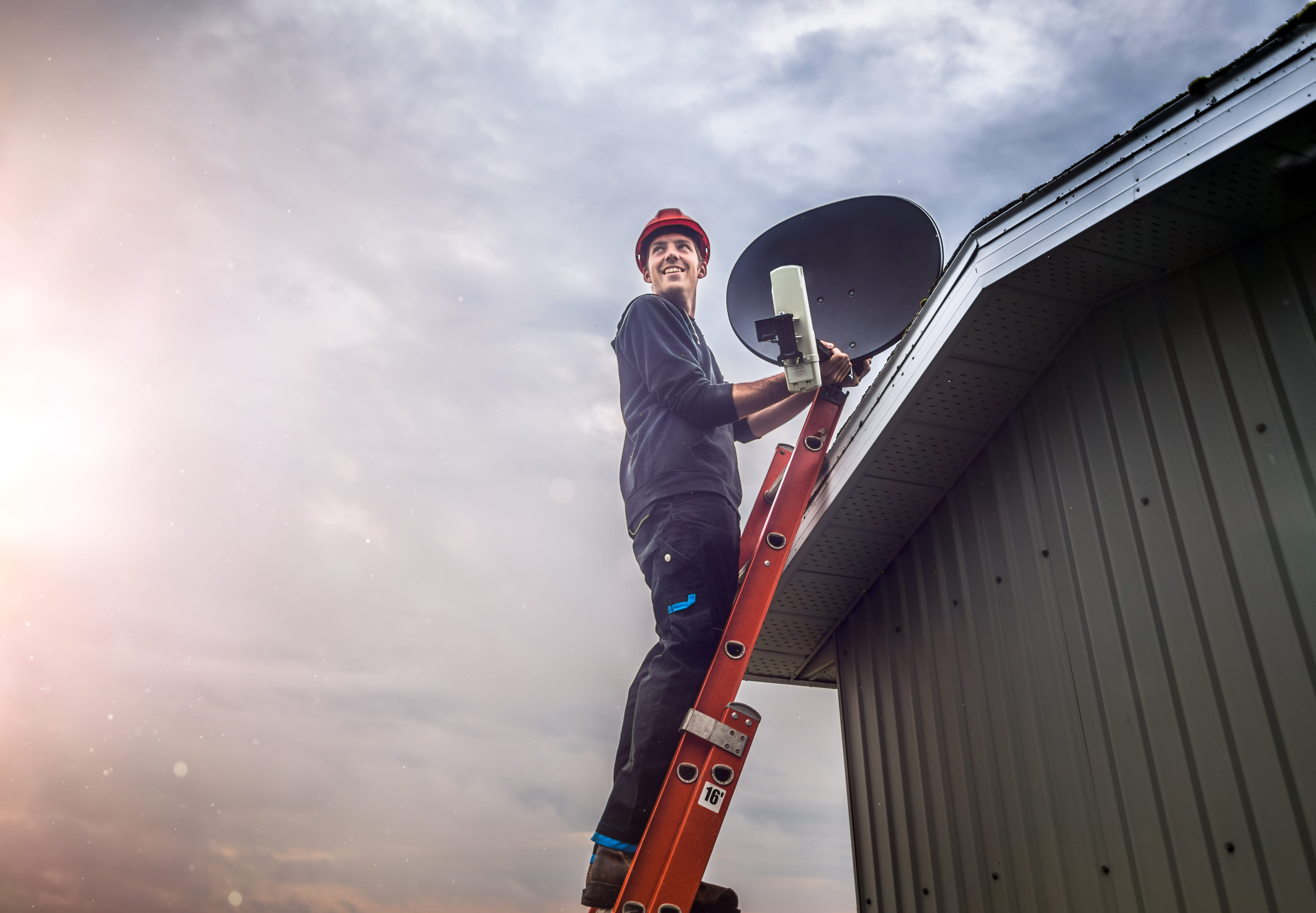 Accredited DSTV technician on a ladder installing a satellite dish at a Benoni home